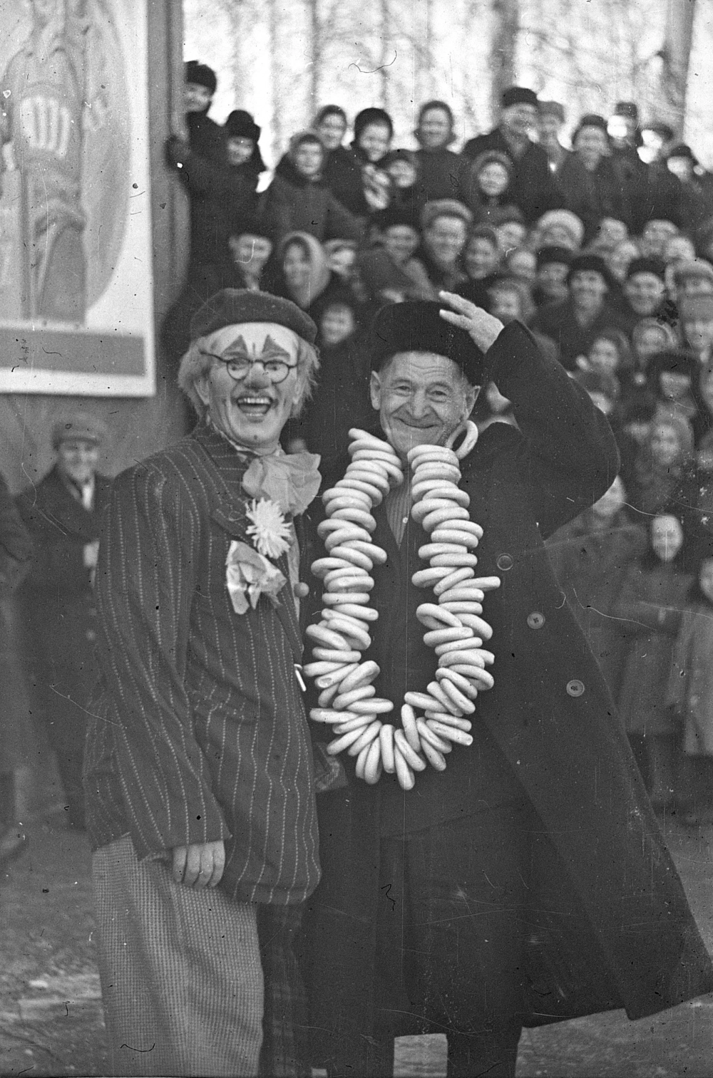 Лазарев Д.Д., пенсионер, получивший приз – связку баранок за отличную пляску «Русская» на празднике «Проводы русской зимы», с клоуном А. Спешневым. 13 марта 1962 г. Автор Л. Чебышева. Нефондовая организация фотодокументов. 0-652.