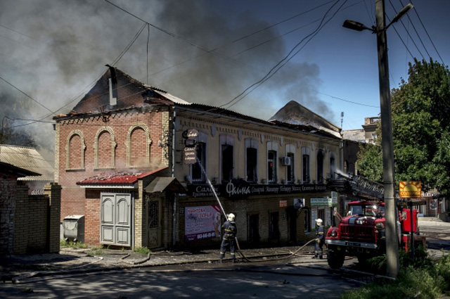 Пожар в здании, загоревшемся в результате попадания снаряда во время артиллерийского обстрела Луганска украинскими силовиками
