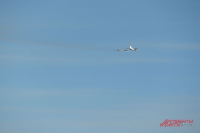 В дымке над головой еле заметны два самолёта. Впереди летит танкер Ил-78, чуть сзади - Ту-95