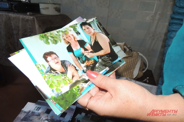 Елена рассматривает фотографии, сделанные до расселения. Она с соседками пьёт чай во дворе собственного дома