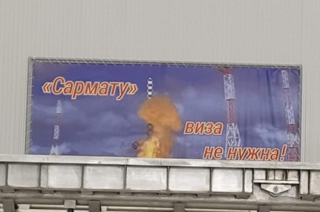 Плакат визит возле макета ракеты.