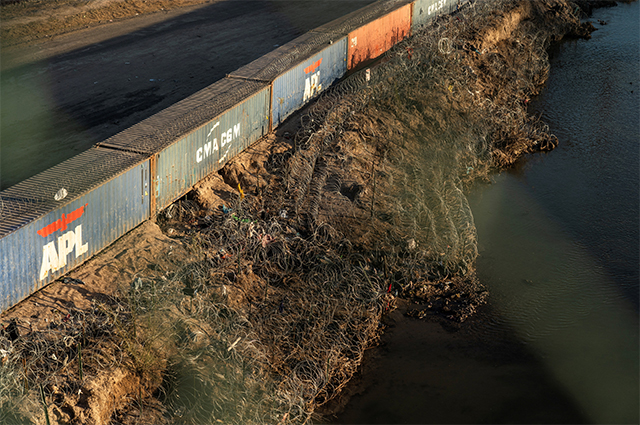 Транспортные контейнеры и проволока-гармошка используются в качестве пограничного ограждения на берегу реки Рио-Гранде в Игл-Пасс, штат Техас.