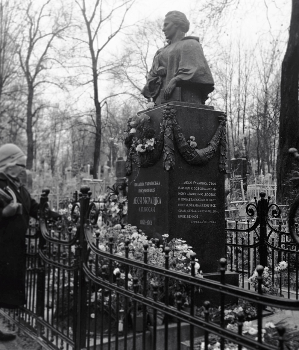 Жительница Киева стоит у могилы Леси Украински на Байковом кладбище.