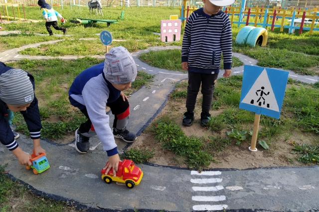 Правила дорожного движения дети изучают в игровом городке с машинами и пешеходными переходами.