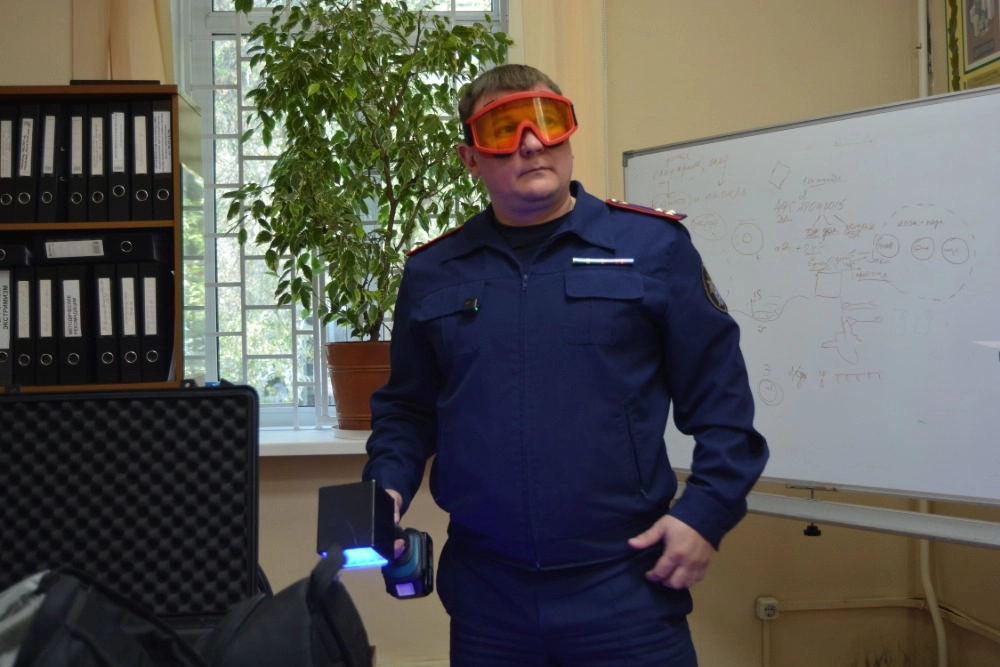 В руках - та самая лампа, в свете которой проявляются невидимые глазу следы.