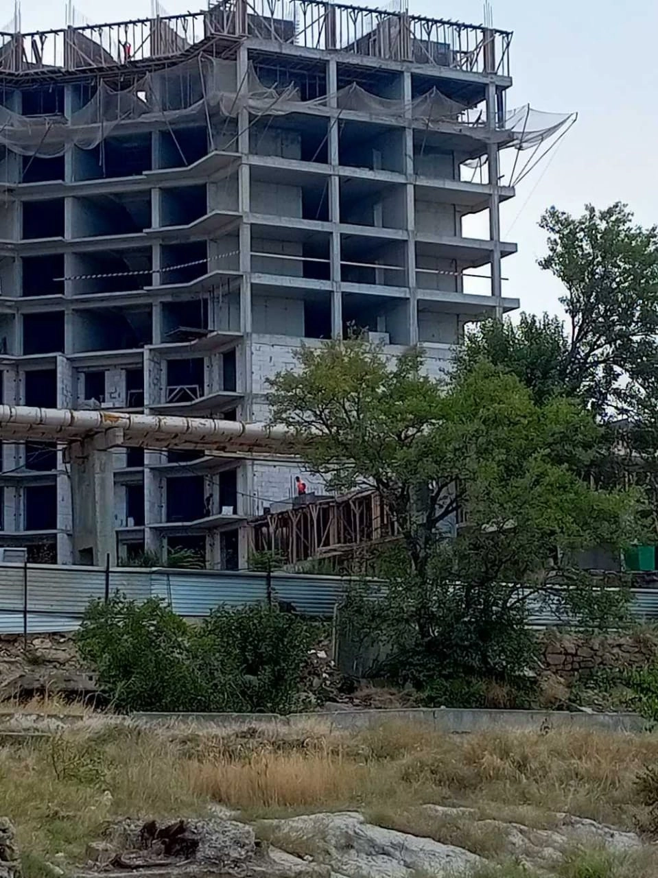 На берегу стоит новая высотка, откуда женщин созерцают строители.