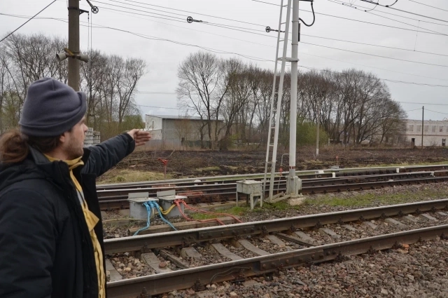 Доброволец-пожарный показывает место у железной дороги, где был пожар.