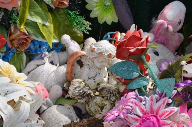 Все игрушки и венки с могилы детей убрали в сторону.