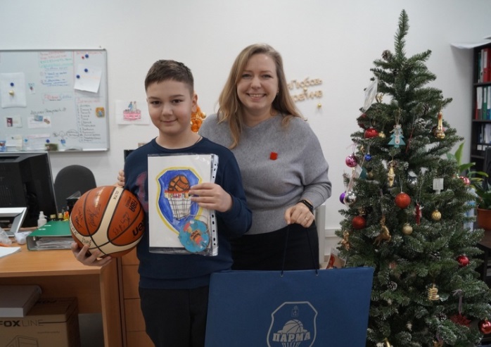 Директор благотворительного фонда «Берегиня» Татьяна Голубаева вручает Артёму подарки, которые передала через фонд его любимая баскетбольная команда.