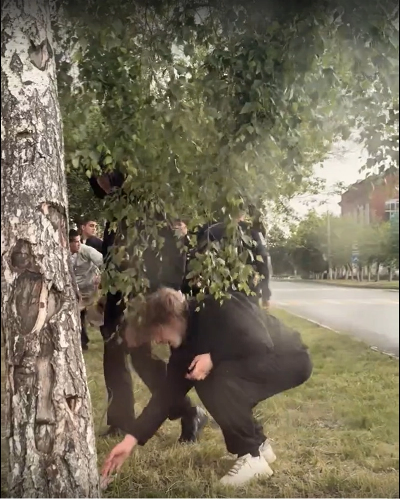 Сергей поднимает свои вещи, а на заднем плане держат одного из агрессоров.