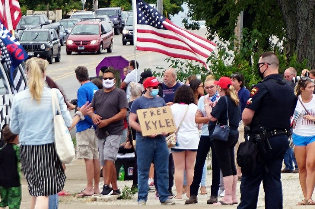 Белый американец держит табличку «Свободу Кайлу» возле средней школы Брэдфорда во время визита президента Дональда Трампа 1 сентября 2020 г.
