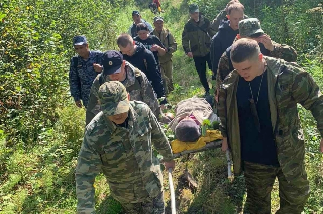 Мужчины выносят измождённую женщину из леса.