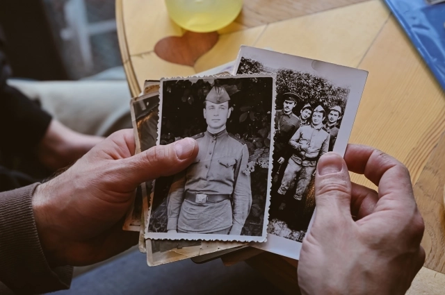 Анатолий и Марфа показывают фронтовые фотографии своих близких.