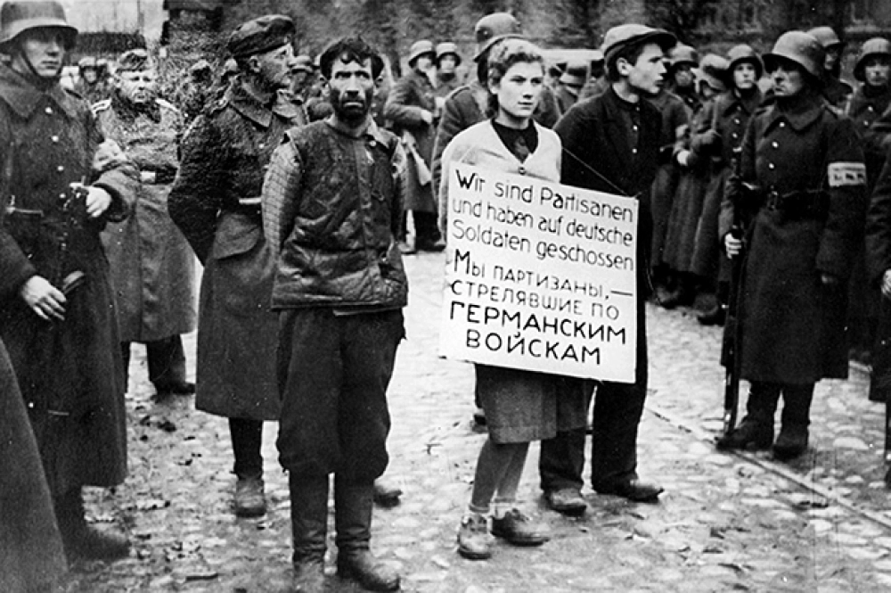 Мария Брускина перед казнью (на фото — в центре со щитом на груди, на щите надпись на немецком и русском языках: «Мы партизаны, стрелявшие по германским войскам»), 26 октября 1941 года.