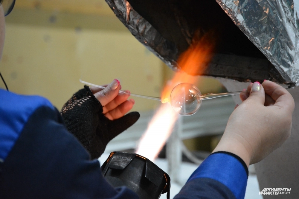 Мастерица нагревает трубку, чтобы через мгновение превратить ее в аккуратный шар.