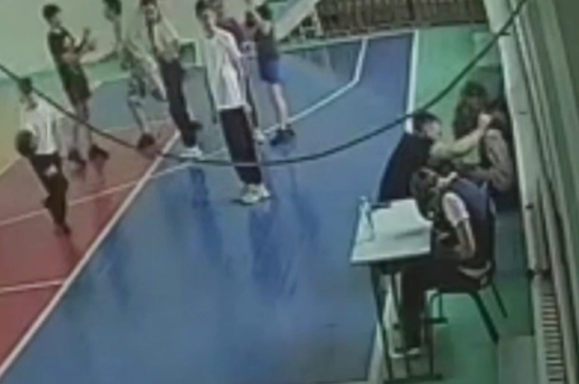 Учитель физкультуры бросил мяч в девочку, сидящую на скамейке.