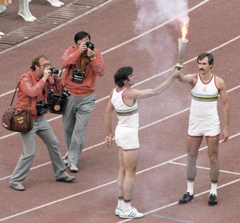 Олимпийский чемпион Сергей Белов (справа) принимает факел с олимпийским огнем из рук трехкратного олимпийского чемпиона Виктора Санеева (слева).