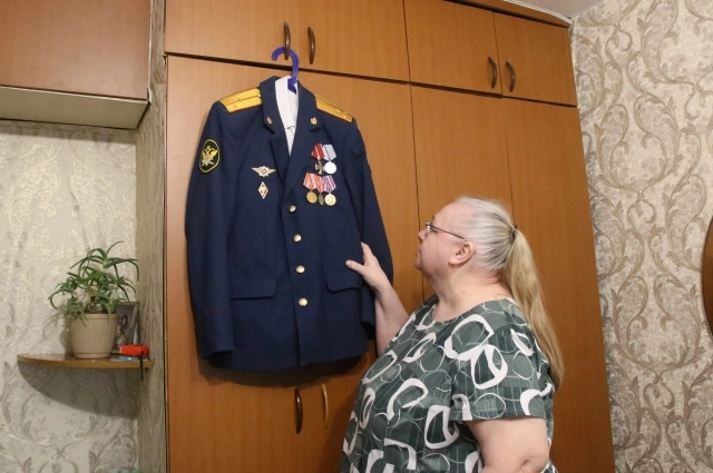 На дверце шкафа висит парадный тёмно-синий китель, увешанный наградами в два ряда.