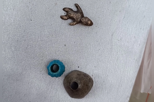 Предметы из могилы мальчика 1,5 лет: бусины и фигурка человечка.