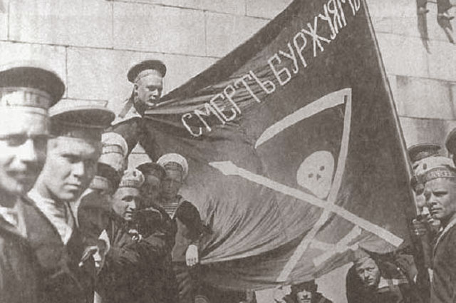 1917 год, революционные матросы Линкора Петропавловск (Балтийский флот) в Гельсингфорсе (ныне Хельсинки) вокруг красного знамени на котором написано «Смерть буржуям!».