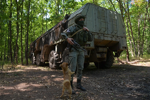 Военнослужащий и собака у оперативно-тактического ракетного комплекса (ОТРК) «Искандер» с крылатыми ракетами, который ведет боевое дежурство в районе проведения специальной военной операции на Украине.