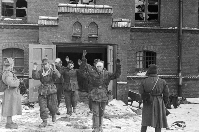 Пленные гитлеровцы выходят из дверей здания под конвоем советских бойцов. Великая Отечественная война 1941-1945 годов