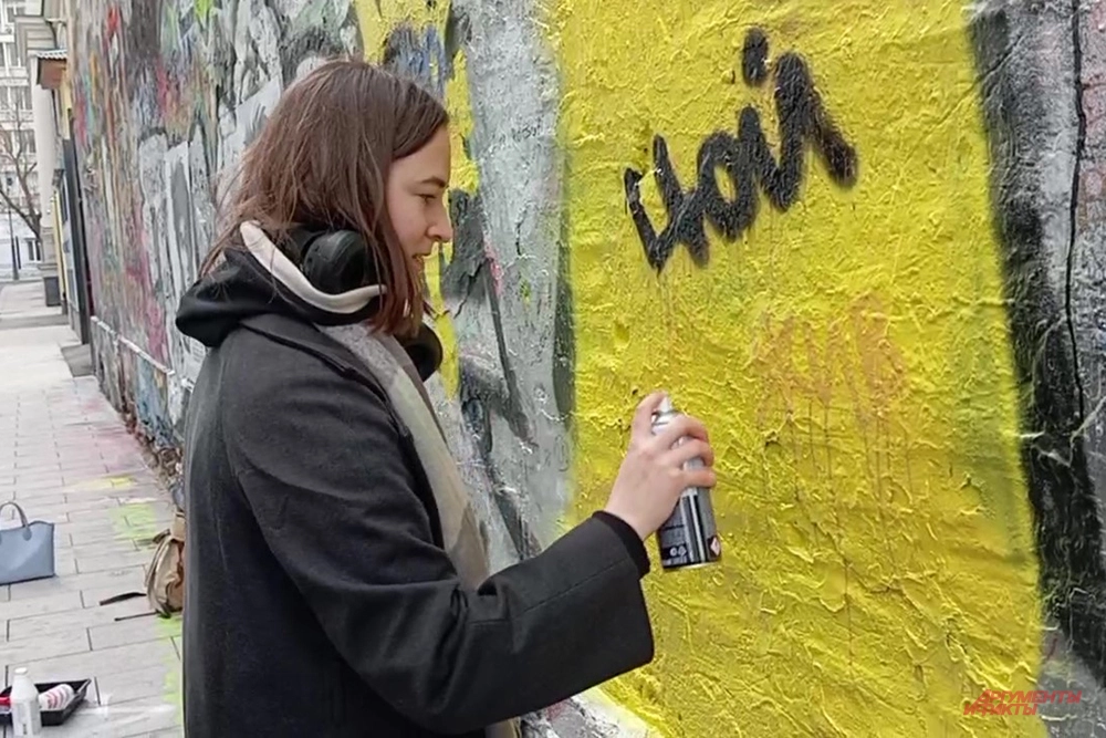 Взрослые поддерживают ребят, расписывающих стену.