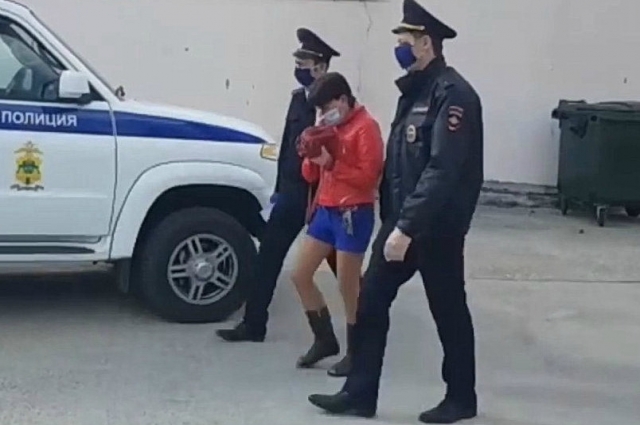 Полицейские ведут Валентину Гусейнову к машине.