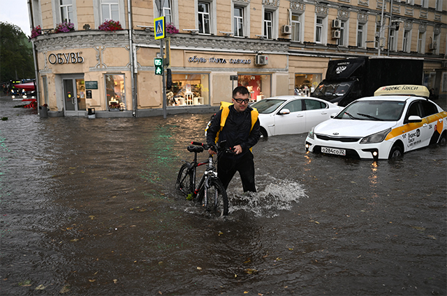Мужчина с велосипедом на подтопленной улице в результате ливня в Москве.
