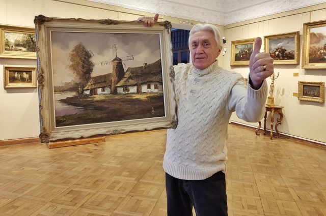 Кирилл Застрожный показывает картину, которую подарил Сергей Пенкин